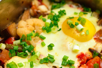 baked mixed vegetables and eggs close view, baking tray with tomatoes, broccoli and spices, home cooking