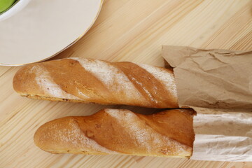 two French baguettes in a paper bag on the table