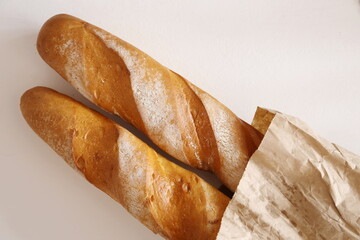 two French baguettes in a paper bag on the table