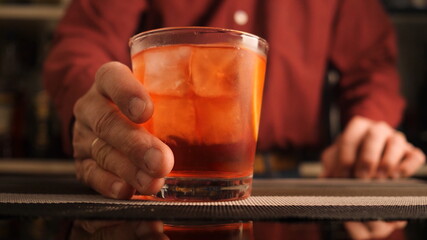 Bartender serves a Negroni cocktail on the bar counter.