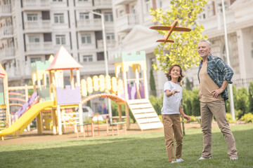 Obraz premium Dark-haired boy playing with a toy plane together with his dad