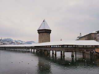 snow covered Kapellbrücke (literally, Chapel Bridge) and Wasserturm (literally, water tower) with...