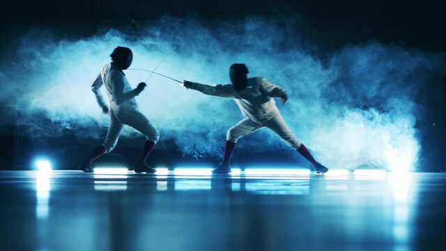 Two sportsmen are fencing in a hall with smoke. Active athlete, fencing concept.