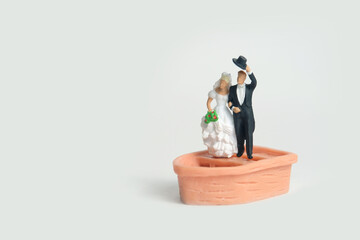 Bride and groom married miniature people stand above boat after wedding, isolated cut out on a white background. Image photo