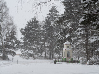 Brick roadside shrine in the forest during heavy snowfall