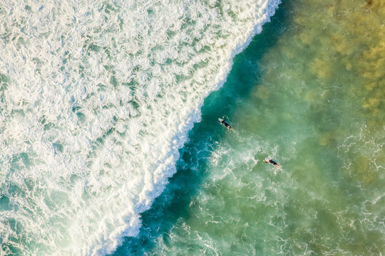 Aerial view of two people doing surf, riding the crispy waves along Alexandra Bay in Queensland, Australia.