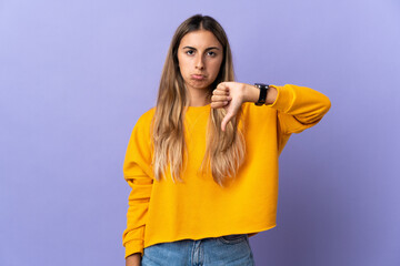 Young hispanic woman over isolated purple background showing thumb down with negative expression