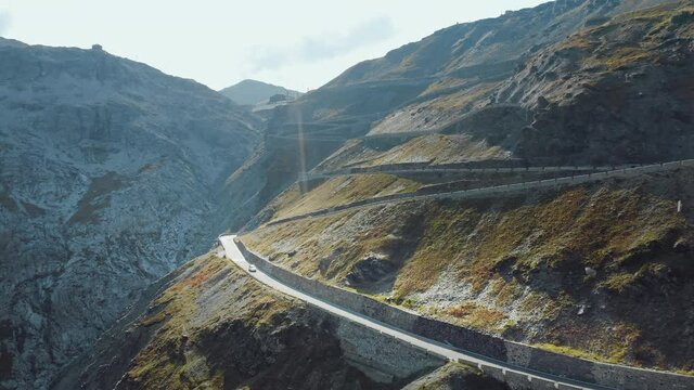 Aerial shot of white car driving on Stelvio Pass with a hairpin corners on a sunny day. Highest paved mountain road in the Eastern Alps. Enjoying the ride.