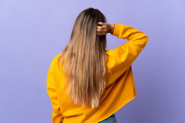 Young hispanic woman over isolated purple background in back position and thinking