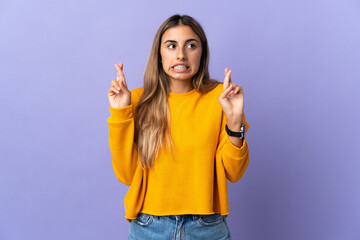 Young hispanic woman over isolated purple background with fingers crossing and wishing the best