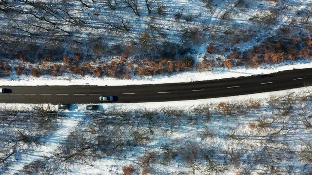 Snowy winter serpentines forest with little traffic on the road on the hill.