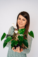 Frau mit Blumenstock, braune Haare, grünes Blumenkleid, Blumen schenken, Freude, moderner Look