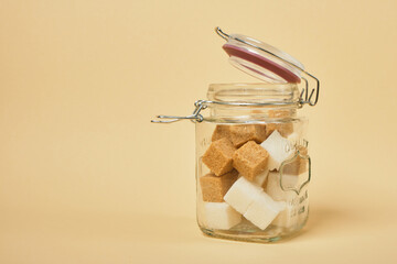 brown and white sugar cubes in a jar with a sealed lid, beige background