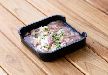 fresh raw pork belly beef sliced on square plate isolated on wooden background, shabu, hot pot ingredients