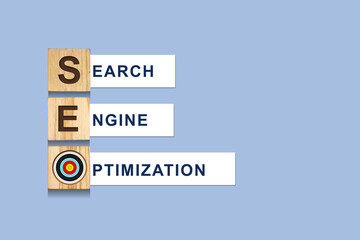SEO concept. Search engine optimization. Word on wooden blocks, over blue background.