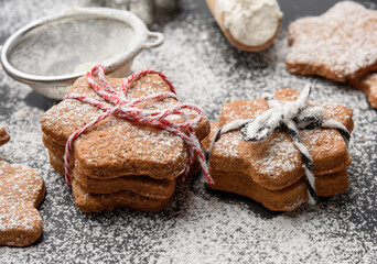 Star shaped baked gingerbread cookies sprinkled with powdered sugar on a black table