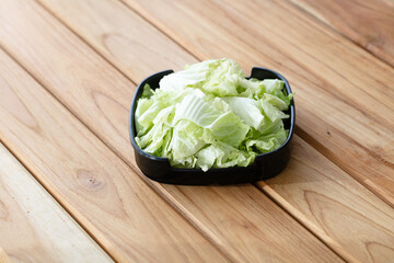 fresh raw chinese cabbage sliced on square plate isolated on wooden background, shabu, hot pot ingredients