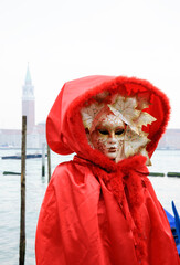 Fototapeta na wymiar Autumn Mask in St Mark's Square square (with view on San Giorgio Maggiore island) during Carnival. Venice, Italy