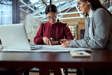 Fototapeta premium Concentrated Asian female person pointing at drawing