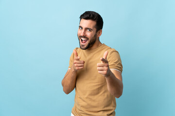 Young handsome man with beard over isolated background pointing to the front and smiling