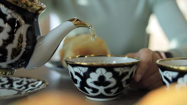 Woman pouring tea from traditional uzbek teapot