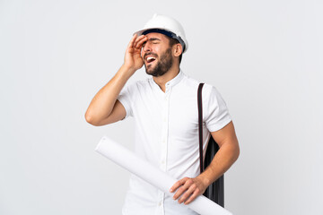 Young architect man with helmet and holding blueprints isolated on white background smiling a lot