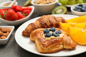 Delicious pastries and orange slices on grey table, closeup. Buffet service
