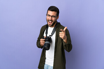 Photographer man over isolated purple background pointing to the front and smiling