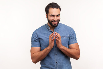 Cunful sneaky man in blue shirt gesticulating with fingers planning devious tricks and cheats,...