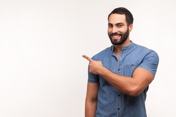 Advertise here! Positive bearded man pointing finger away paying your attention at empty space for...