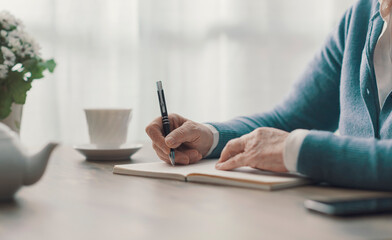 Senior woman writing on a notebook