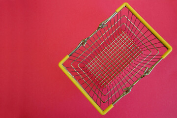 close up metal basket with yellow handles from supermarket on pink background top view . online...