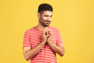 Sneaky cunful man with beard in striped red t-shirt drumming fingers planning devious pranks,...