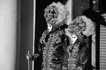 Noble couple masks at St Mark's Square during traditional Carnival. Venice, Italy. Black white historic photo
