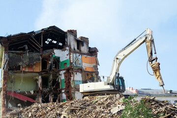 excavator demolishing a brick building. Machinery Demolishing Building