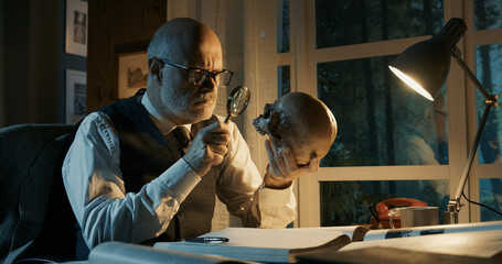 Professor sitting at desk and checking a human skull