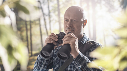 Tourist walking in a forest and using binoculars