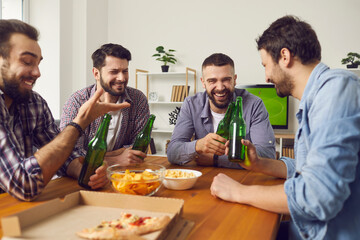 Home gathering with beer and food for male company. Four cheerful men friends talking during home party sitting at table with beer pizza and snacks together having fun