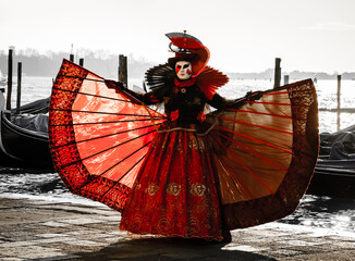 A mask in red in St Mark's Square embankment near the gondolas during the Carnival in Venice, Italy.