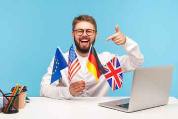 Positive smiling man in eyeglasses holding flags of usa, german, great britain and europe...