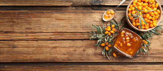 Obraz na płótnie Canvas Delicious sea buckthorn jam and fresh berries on wooden table, flat lay. Banner design with space for text