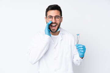 Dentist man holding tools isolated on white background shouting with mouth wide open