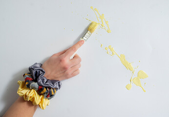 a female hand holding a fringe brush and wearing colorful hair ornaments on her hands. Yellow color