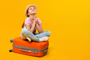 The child sits on a suitcase and, closing his eyes, dreams of travel, adventure, vacation. Little...