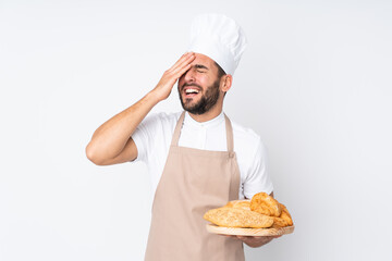 Male baker holding a table with several breads isolated on white background laughing