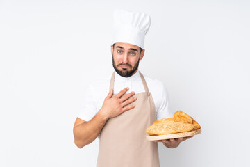 Male baker holding a table with several breads isolated on white background pleading