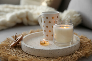 Cup of drink and burning candles on sofa in room. Interior elements