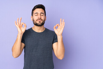 Caucasian handsome man in zen pose over isolated purple background - obrazy, fototapety, plakaty