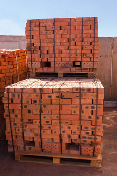 Common red bricks on the pallets on a warehouse