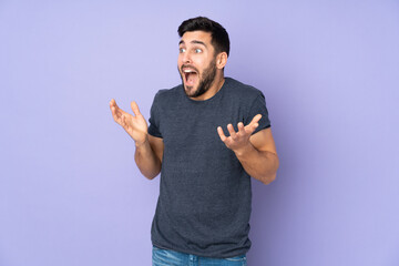 Caucasian handsome man with surprise facial expression over isolated purple background